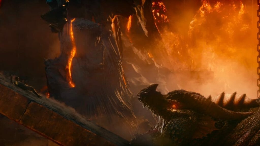 Chris Pine slides down a steep rocky slope and heads towards the giant open mouth of a fat and hungry red dragon in the movie DUNGEONS & DRAGONS: HONOR AMONG THIEVES.