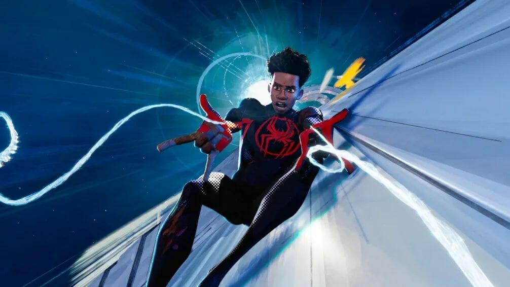 Miles Morales in his Spider-Man costume without wearing a mask shoots his webs with both hands as he rides on top of a futuristic silver colored speeding train in the sky in SPIDER-MAN: ACROSS THE SPIDER-VERSE. 