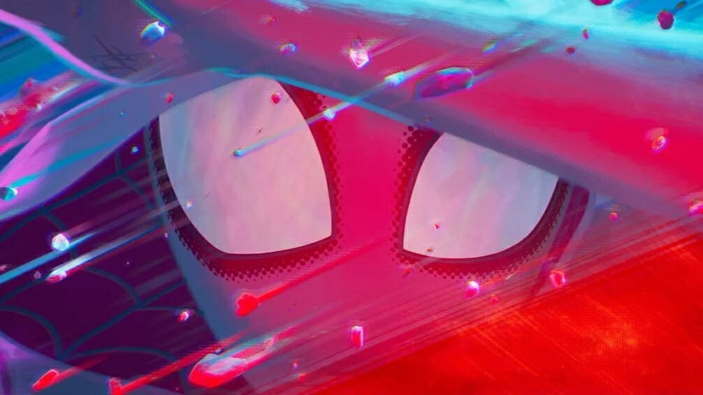 A close up of Spider-Gwen as she tries to cover her face during an explosion animated with red, pink, purple, and blue watercolors in the sequel SPIDER-MAN: ACROSS THE SPIDER-VERSE. 
