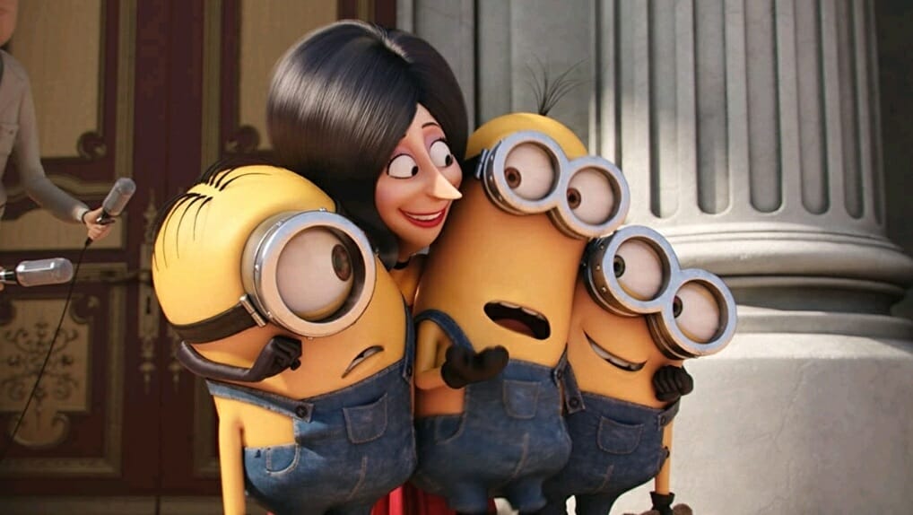 The evil villain Scarlet Overkill voiced by Sandra Bullock hugs the 3 yellow minions named Kevin, Stuart, and Bob in the first MINIONS prequel movie from Illumination.