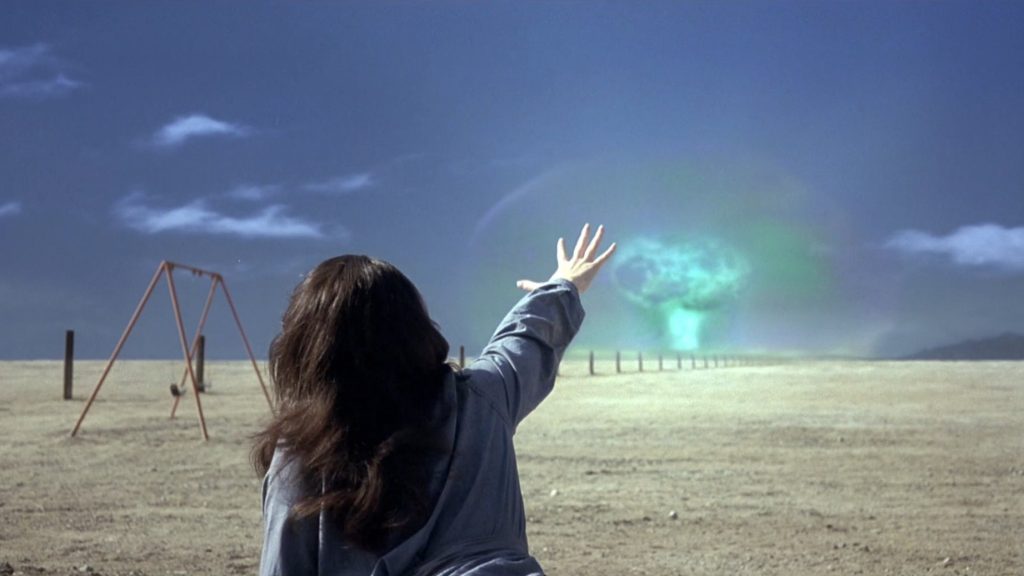 Bruce Banner's mom Edith reaches her hand out towards a green mushroom cloud explosion in the distance of an empty desert in the 2003 HULK movie directed by Ang Lee.