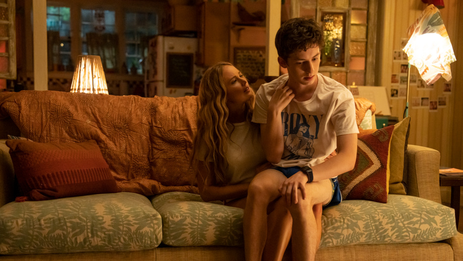 Maddie played by Jennifer Lawrence tries to seduce the younger Percy played by Andrew Barth Feldman by cuddling with him on a couch as he tries to awkwardly keep his hands to himself in the raunchy comedy film NO HARD FEELINGS.