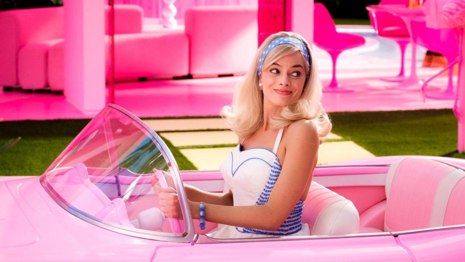 Margot Robbie stars as Barbie riding in her pink Corvette across the pink Barbie Land in the 2023 film.