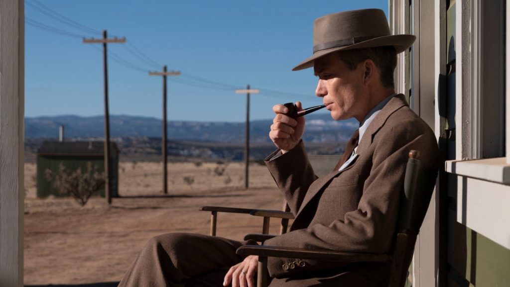 Cillian Murphy as J. Robert Oppenheimer smokes his pipe on a porch in the secret Los Alamos, New Mexico government facility in Christopher Nolan's OPPENHEIMER.