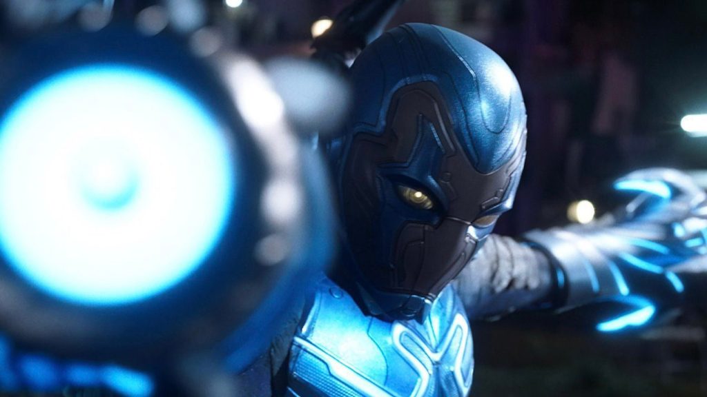 Blue Beetle prepares to shoot energy beams from his hand blasters in the new DC movie.