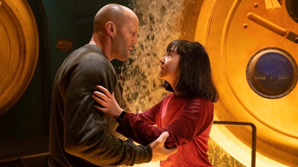Jason Statham and Sophia Cai hold each other with sighs of relief in an underwater facility in MEG 2: THE TRENCH.