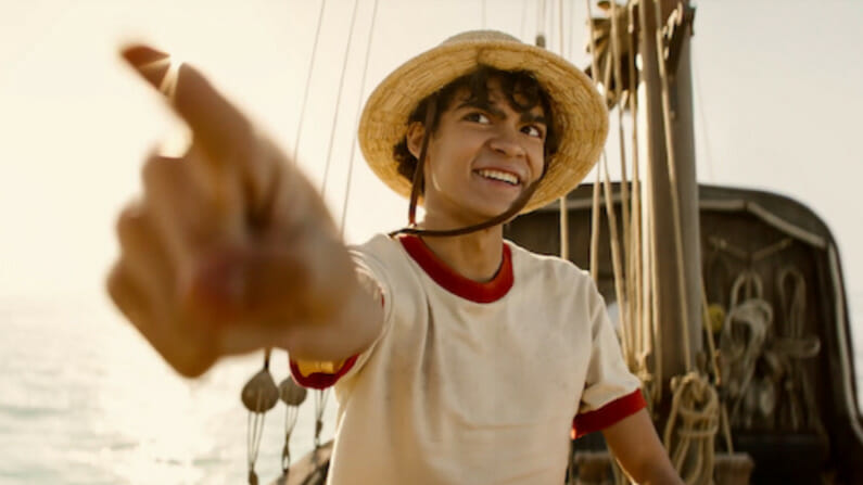 Iñaki Godoy stars as the boy pirate Monkey D. Luffy wearing his iconic straw hat and pointing to the sky in the live-action ONE PIECE series on Netflix.