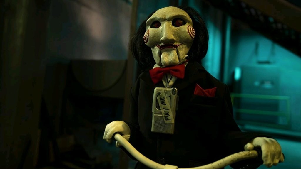 Billy the Puppet is placed on a small tricycle with an audio tape placed around his neck that reads "play me" in SAW X releasing in September 2023. 