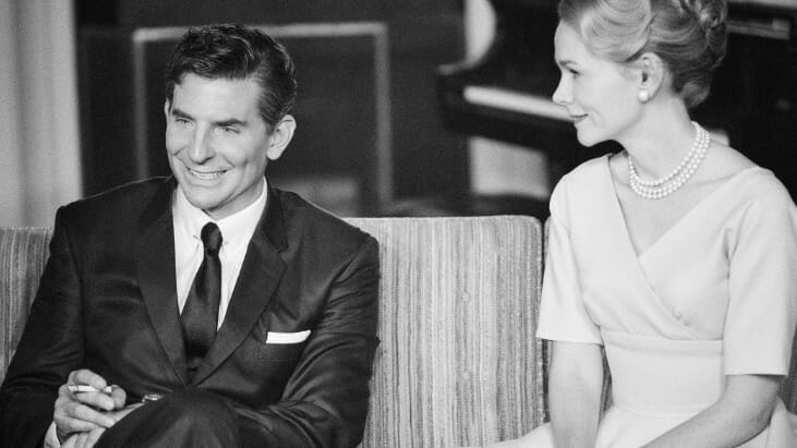 Bradley Cooper as Leonard Bernstein and Carey Mulligan as Felicia Montealegre pose together on a couch in a black-and-white shot from the biopic MAESTRO on Netflix.