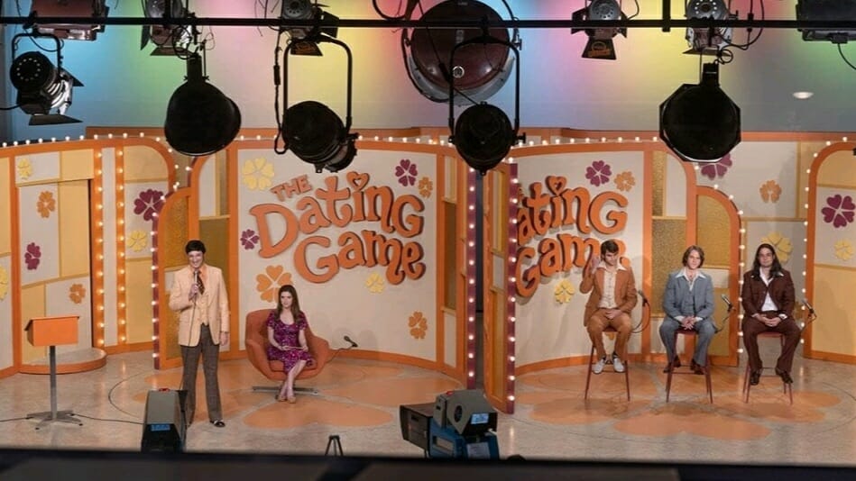 An episode of The Dating Game TV show being filmed in front of a live studio audience with host Jim Lange played by Tony Hale and female bachelorette Cheryl Bradshaw played by Anna Kendrick in the movie WOMAN OF THE HOUR. 