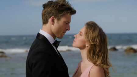 Glen Powell and Sydney Sweeney get close together in an intense stare down in front of a beach in Australia in the rom-com ANYONE BUT YOU.