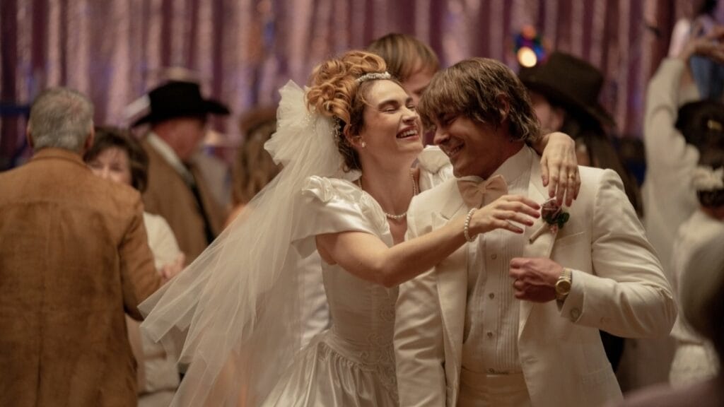 The newly wed couple Pam and Kevin Von Erich played by Lily James and Zac Efron celebrate and dance together at their wedding in the A24 movie THE IRON CLAW.