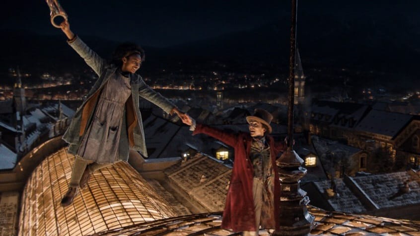 Timothee Chalamet and Calah Lane perform a magical musical number on top of a building as Lane floats away holding balloons in the movie WONKA.