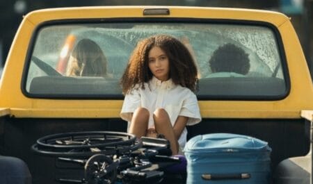 Nico Parker as the teenager Doris looks embarrassed as she sits in the back on her mom's pick up truck after being picked up from school in the coming-of-age drama film SUNCOAST streaming only on Hulu.