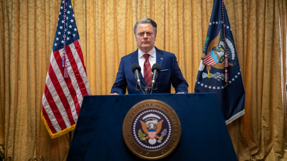 The authoritarian President of the United States played by Nick Offerman stands at his podium ready to give a speech in CIVIL WAR written and directed by Alex Garland. 