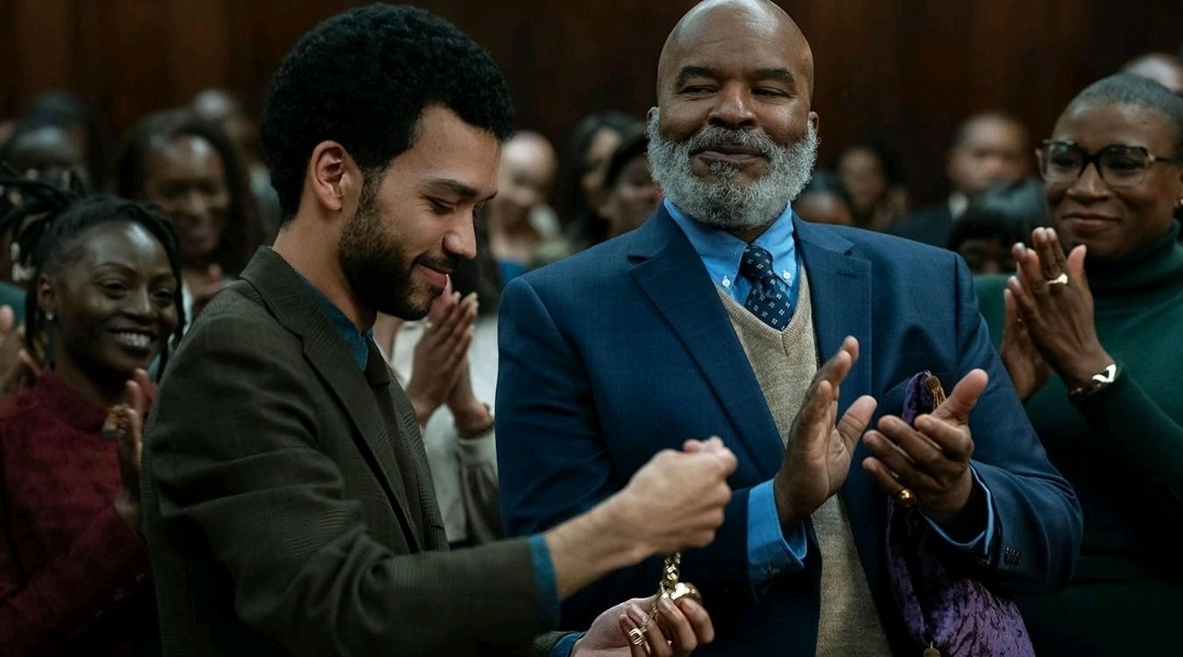 Justice Smith receives a gold pocket watch as he's inducted into a secret magical society while David Alan Grier and his other Black colleagues clap around him with huge smiles in THE AMERICAN SOCIETY OF MAGICAL NEGROES film.