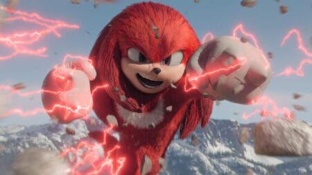 Knuckles the Echidna smashes a boulder with a huge smile and red electric energy coming from his fists in the KNUCKLES miniseries streaming only on Paramount+.