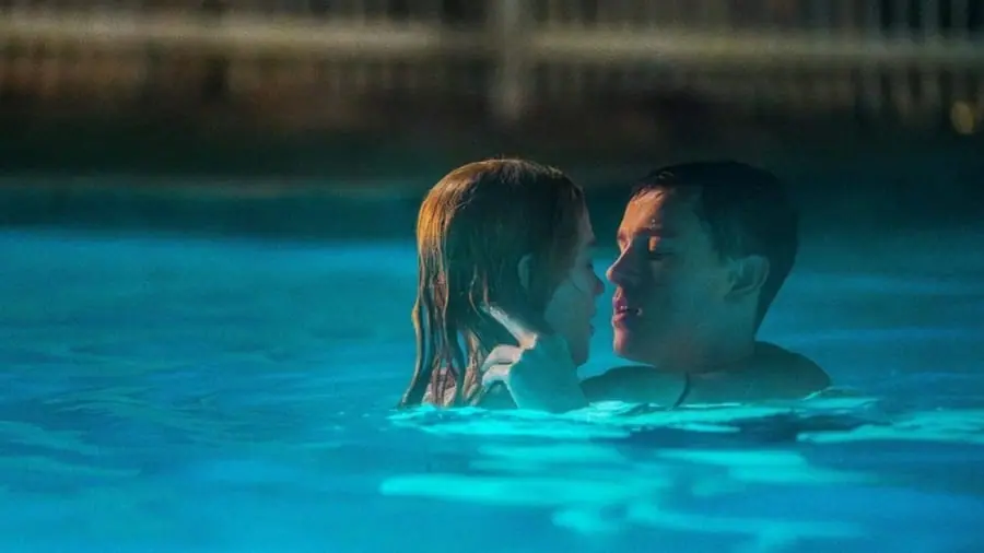 Nicole Kidman and Harris Dickinson embrace each other for a kiss while swimming together in a large empty pool in the movie BABYGIRL. 