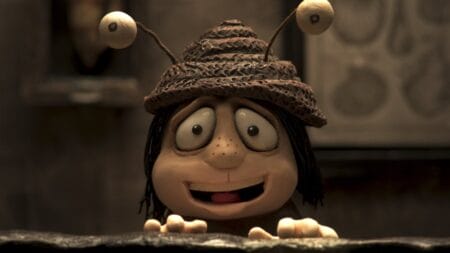 A young girl named Grace wears a makeshift snail hat with two antenna eye balls in the stop-motion animated film MEMOIR OF A SNAIL.