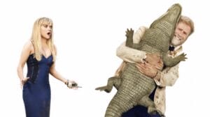 Reese Witherspoon looks shocked at Will Ferrell holding up a wild alligator while wearing a white tuxedo in the hilarious comedy YOU'RE CORDIALLY INVITED, coming to the Prime Video streaming service in January 2025.