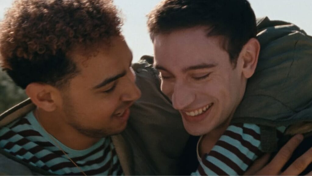 ‘Lurker’ Review – An Unpredictable Tale of Power Dynamics Between Fan and Artist | Sundance 2025 Archie-Madekwe as the rising pop star Oliver throws his arms around his new best friend Matthew, played by Théodore Pellerin, as the two share a smile together in the psychological thriller film LURKER.