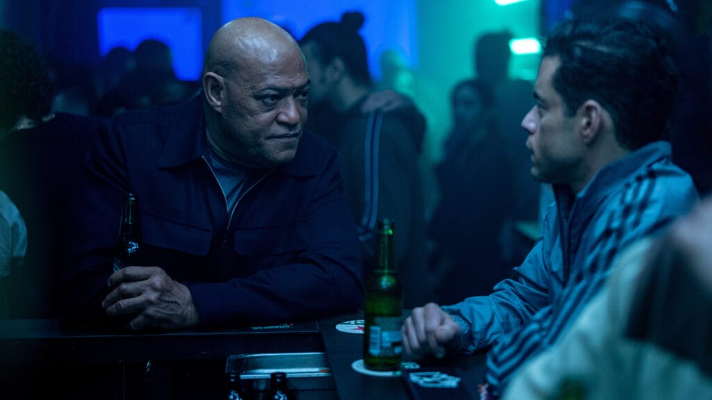 Lawrence Fishburne and Rami Malek share a few beers at a covert bar in the espionage thriller THE AMATEUR.
