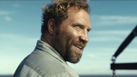 ‘Dangerous Animals’ Review – Jai Courtney Effortlessly Steals Serial Killer/Shark Horror Movie Hybrid A close-up of Jai Courtney looking over his shoulder with a demented smile as the shark-obsessed serial killer Tucker in the new horror movie DANGEROUS ANIMALS.