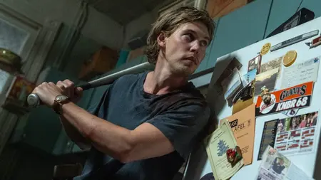 Austin Butler holds up a large baseball bat as he prepares to swing at an intruder in his crummy New York City apartment in the late '90s-set crime thriller CAUGHT STEALING.