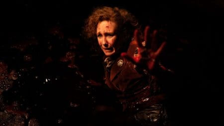 Vera Farmiga stars as paranormal investigator Lorraine Warren holding up her hand covered in blood with great despair in THE CONJURING: LAST RITES.