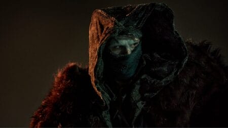 Jacob Elordi stars as Frankenstein's Monster covered in a large cloak and prosthetic face makeup in the 2025 movie adaptation directed by Guillermo del Toro.