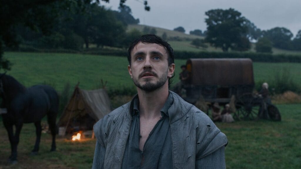 Paul Mescal stars as William Shakespeare dramatically standing in front of the desolate backdrop of a beautiful 16-century English countryside in Chloé Zhao's HAMNET film.