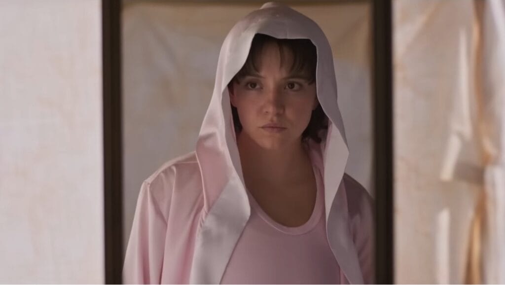 Sydney Sweeney wears a pink boxing robe as she stares at herself in the mirror with anger in the titular sports biopic about famous female boxer Christy Martin.