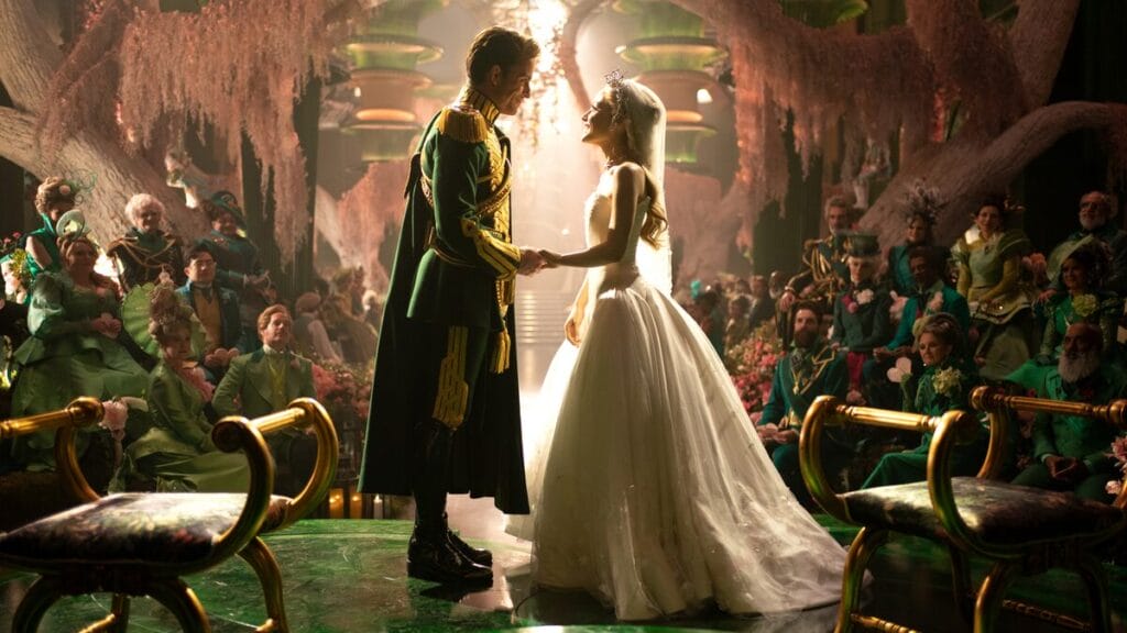 Jonathan Bailey as Fiyero Tigelaar in his Wizard's Guard uniform and Glinda the Good in a beautiful white wedding dress get married in front of a large crowd in the Emerald City in the movie musical sequel WICKED: FOR GOOD.