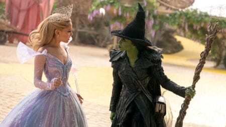 Ariana Grande as Glinda the Good and Cynthia Erivo as Elphaba Thropp, aka the Wicked Witch of the West, square off on the yellow brick road in the middle of munchkinland wearing their new updated costumes in the movie musical WICKED: FOR GOOD.