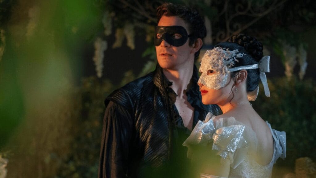 Benedict Bridgerton and Sophie Baek hold each other tight in a lavish garden with moody lighting while wearing black and silver masquerade masks in BRIDGERTON Season 4, which is included in the Netflix January 2026 list of new movies and TV shows.