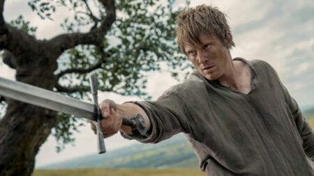 Peter Claffey stars as the titular Hedge Knight holding up his shiny sword during a tense battle in the Game of Thrones spin-off series A KNIGHT OF THE SEVEN KINGDOMS, which is included in the HBO Max January 2026 list of new movies and TV shows.