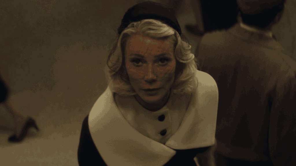 Gwyneth Paltrow stars as Old Hollywood starlet Kay Stone looking up to the camera while wearing a beautiful veil and white-collared coat in the A24 period movie MARTY SUPREME.