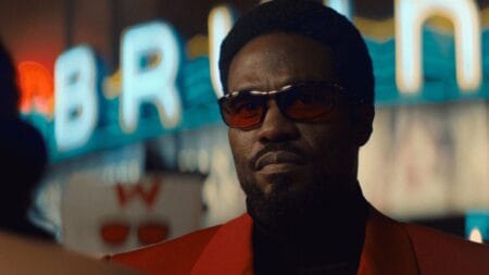 Yahya Abdul-Mateen II stars as the super-powered actor Simon Williams looking cool while sporting a red blazer with dark red sunglasses in Marvel's WONDER MAN show on Disney+.