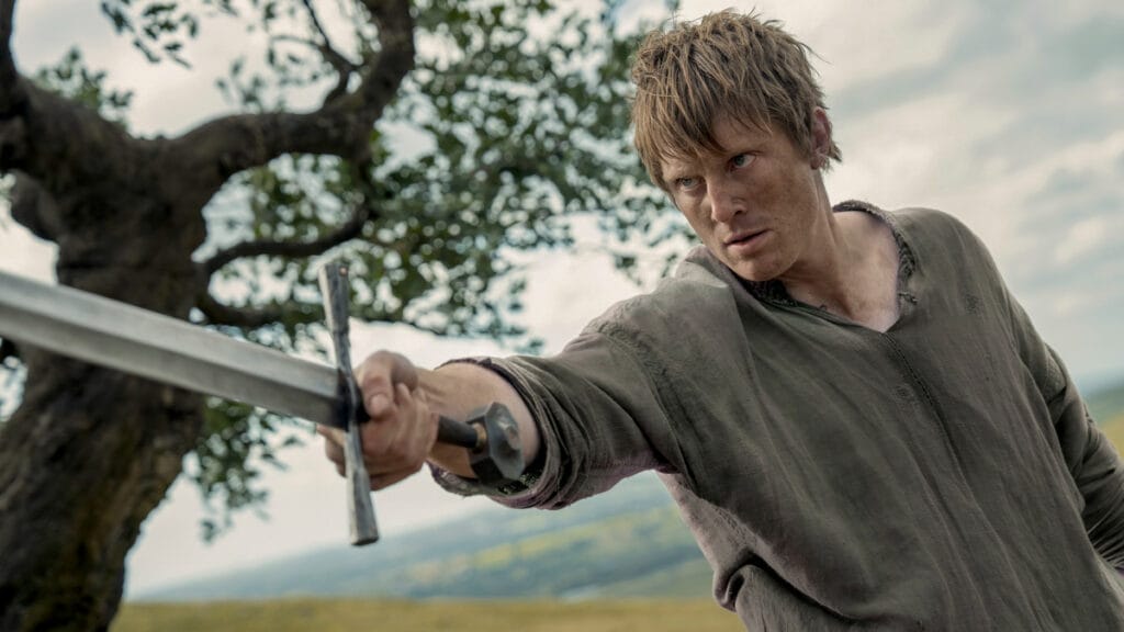 Peter Claffey stars as Ser Duncan the Tall raising his large and shiny sword towards the camera in an epic battle shot from the Game of Thrones spin-off show A KNIGHT OF THE SEVEN KINGDOMS.