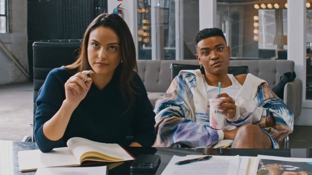 Camila Mendes and Owen Thiele star as slick reality TV producers sitting at their desk during auditions for their new fashion competition show in the satirical comedy IDIOTKA.