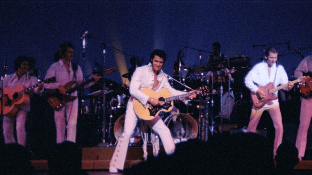 Restored footage from the EPiC concert movie of Elvis Presley playing his guitar on stage in his iconic white leather jump suit with his band during his Las Vegas residency.