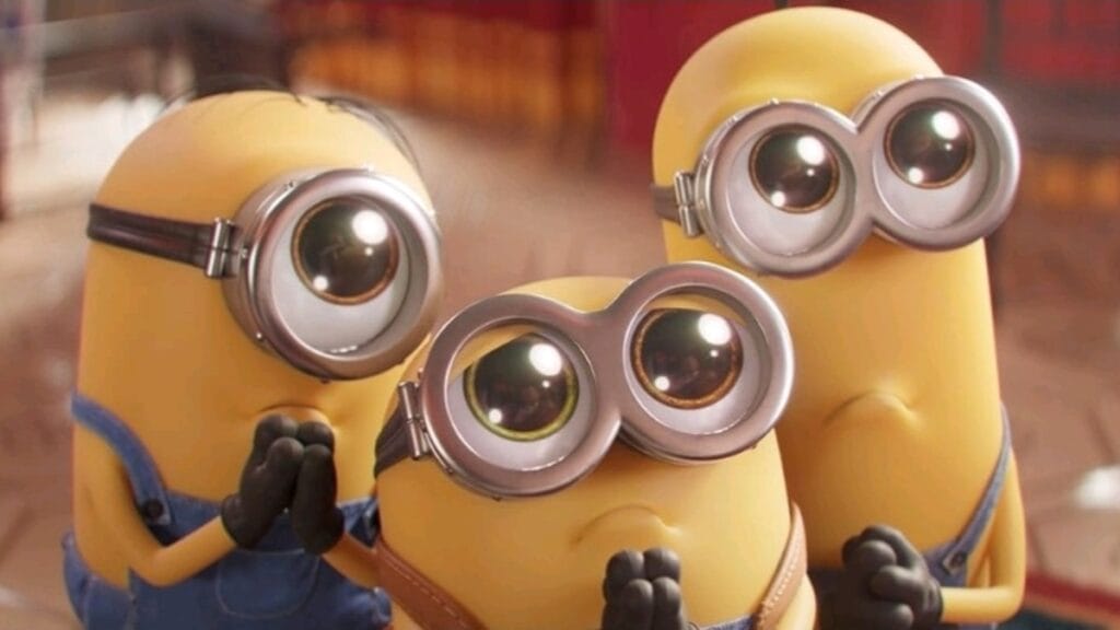 Gru's yellow minions Kevin, Stuart, and Bob huddle together and make adorable sad puppy dog faces with their big eye goggles shinning bright in the sunlight. 