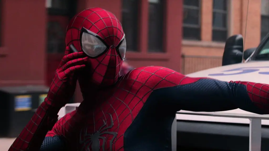 Spider-Man, played by Andrew Garfield, answers the phone while hanging onto the front side of a large truck during the opening chance sequence of THE AMAZING SPIDER-MAN 2.