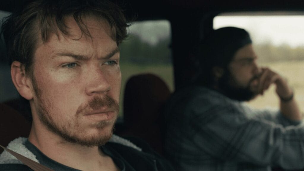A close-up shot of Will Poulter and Noah Centineo riding in a car together with somber facial expressions in the opioid addiction drama UNION COUNTY.