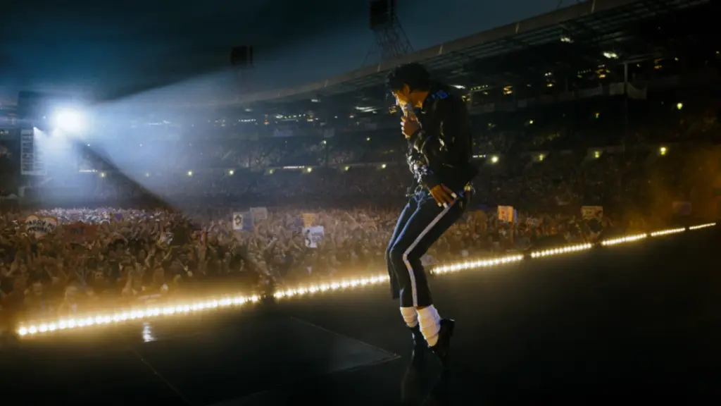 An epic shot of Michael Jackson striking a dance pose on stage while singing "Bad" at Wembley Stadium in 1988, as recreated in the biopic starring Jaafar Jackson. 