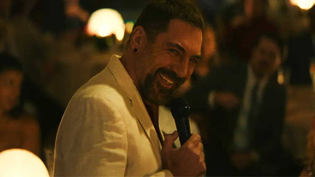 Javier Bardem gives a sinister smile while wearing a sleek white suit as the mysterious villain Max Cady in the Apple TV+ version of CAPE FEAR.