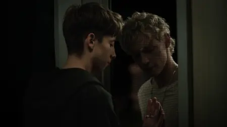 Joe Bird and Stacy Clausen try to embrace each other and press each other's hands through a screen door in the queer horror movie LEVITICUS.
