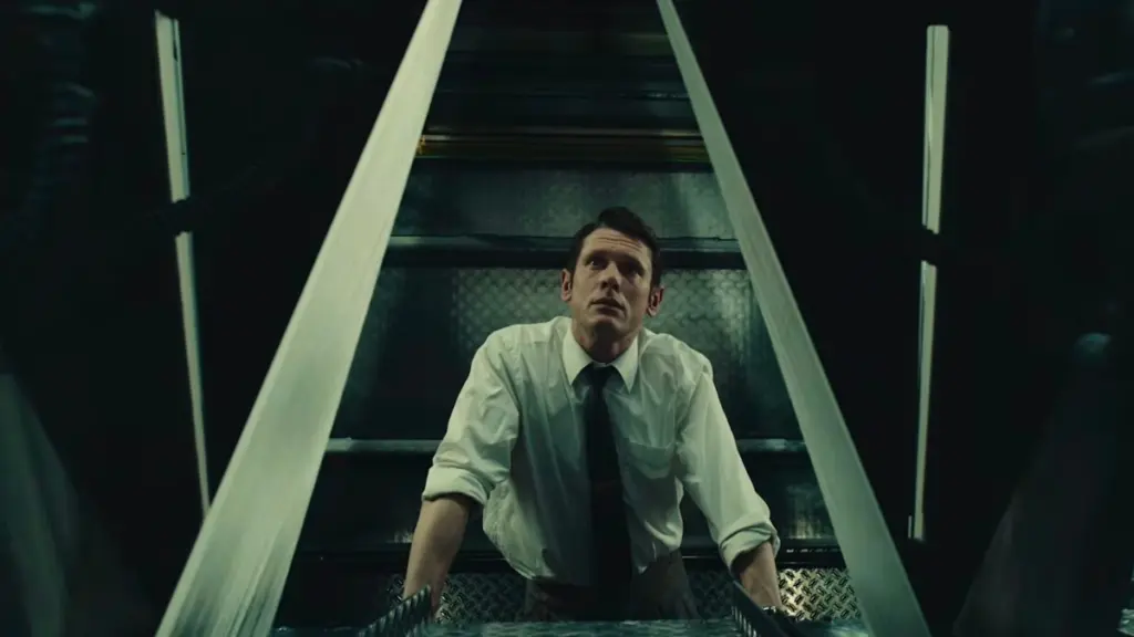 Jack O'Connell stars as head editor of The Sun tabloid newspaper Larry Lamb standing between two large printing presses in a stylish shot from Danny Boyle’s INK.