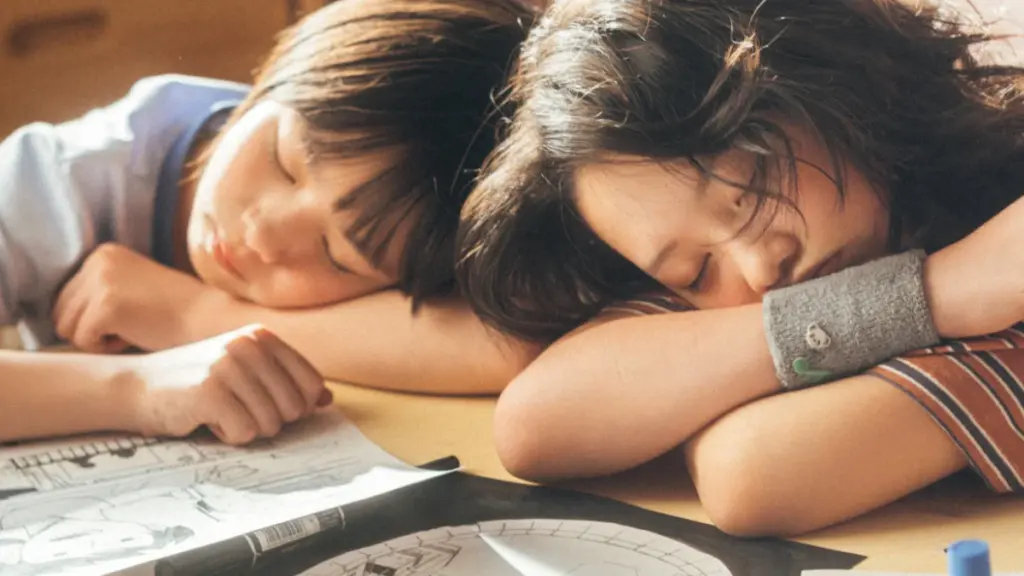 The young versions of Kyomoto and Fujino, played by Furi Nanasa and Rokka Okada, sleep side by side with their heads rested on their desks covered in Manga comic strips in the live-action LOOK BACK film.