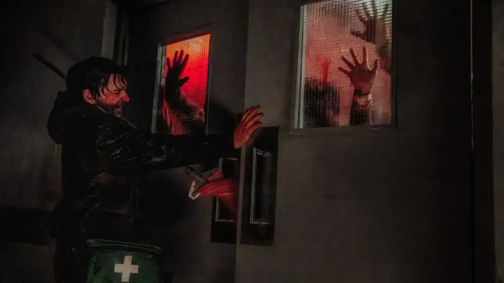 Austin Abrams struggles to hold a large hospital door closed while its being pushed by a horde of zombies in RESIDENT EVIL. 